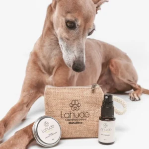 Galgo junto al neceser de Lahude, bálsamo hidratante regenerador y spray reparador en tamaño mini.