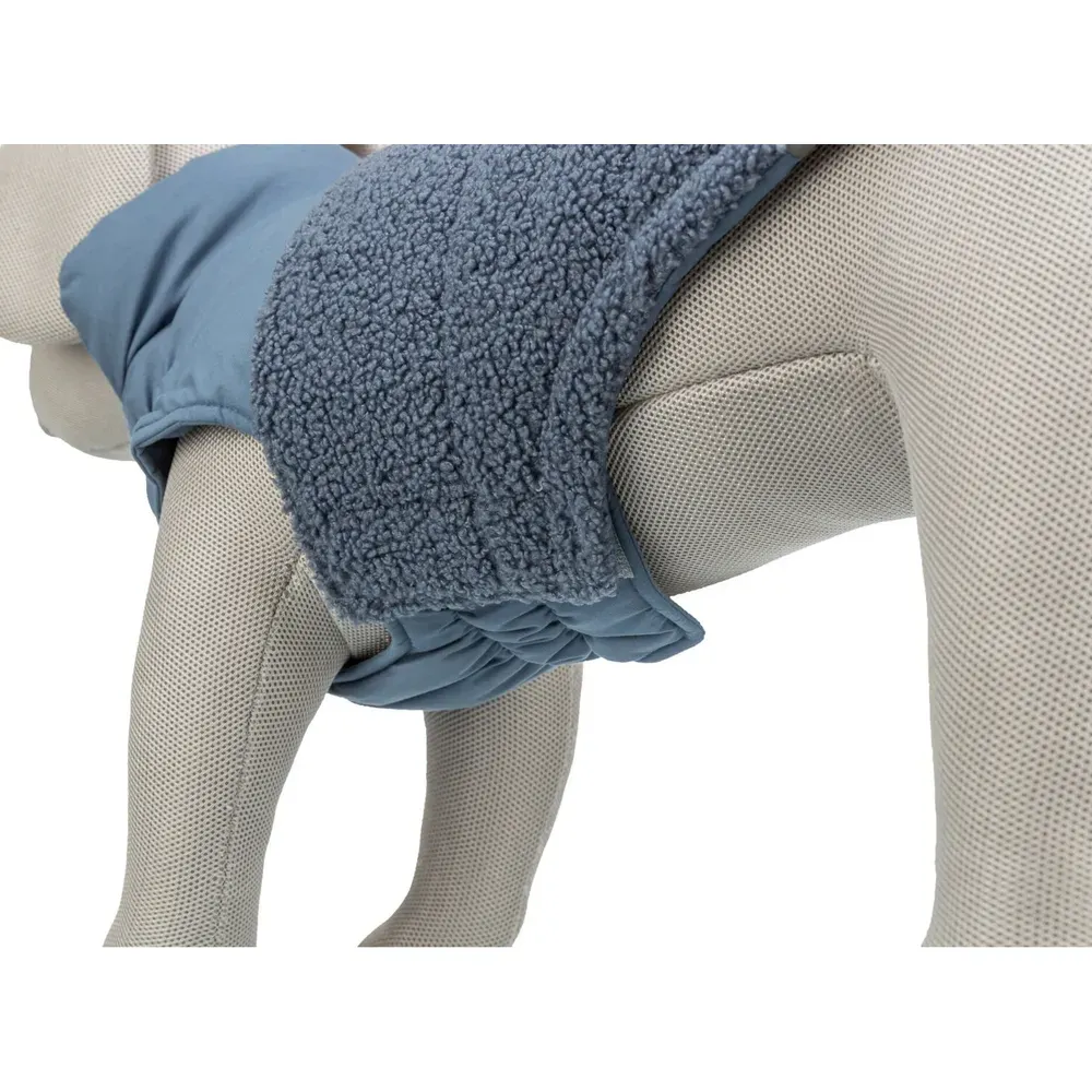 Detalle del abrigo Trixie Ajou azul para perro, mostrando costado acolchado y ajuste bajo el abdomen